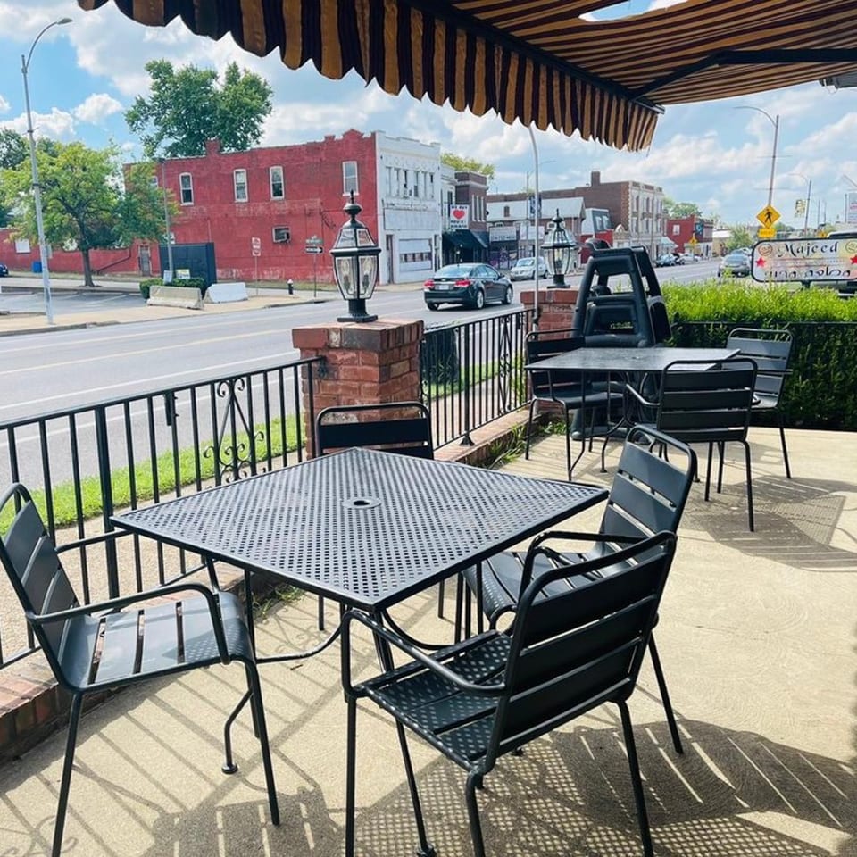 Majeed Mediterranean Restaurant's outdoor patio with black tables and chairs under a striped awning.