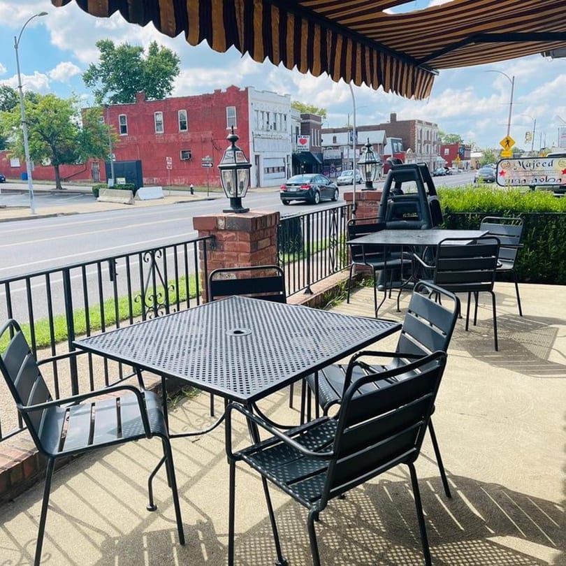 Majeed Mediterranean Restaurant's outdoor patio with black tables and chairs under a striped awning.